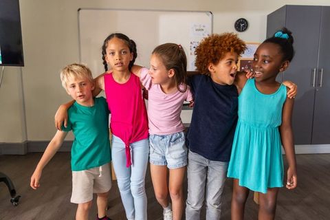 Kids linking arms in classroom celebrating friendship, diversity and teamwork