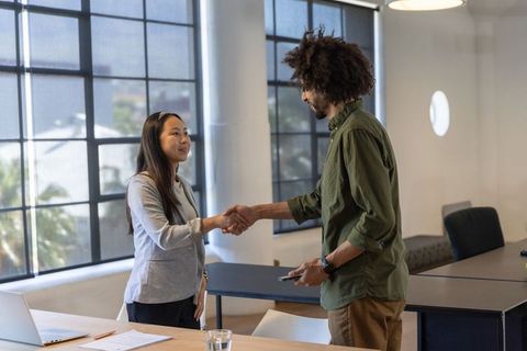 Diverse Coworkers Shaking Hands in Modern Office Setting