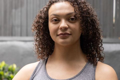 Confident young woman portrait outdoor patio wearing gray tank top and natural curly hair