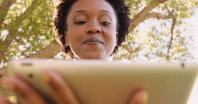 Smiling Woman Using Tablet Under Tree in Park - Download Free Stock Images Pikwizard.com