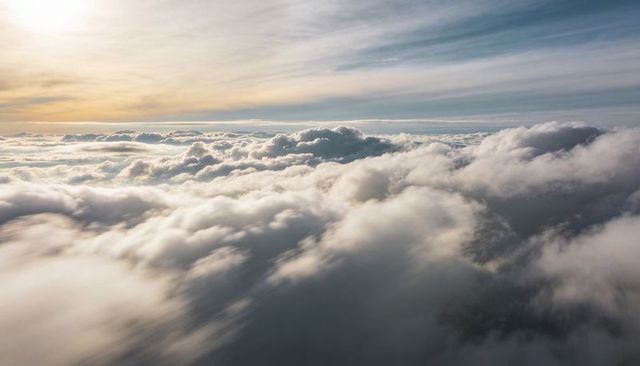Glowing Dawn Cloudscape Flowing Over High-Altitude Horizon With Golden Light
