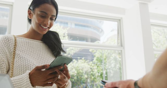 Smiling Woman Using Smartphone for Payment in Bright Room - Download Free Stock Images Pikwizard.com