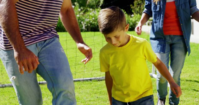 A young Caucasian boy in a yellow shirt is walking through a park with adults, with copy space. It's a sunny day, and the group seems to be enjoying a leisurely stroll together.