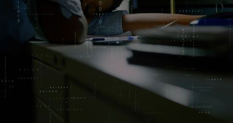 Woman leaning on study desk with smartphone and pen under binary code overlay, low light