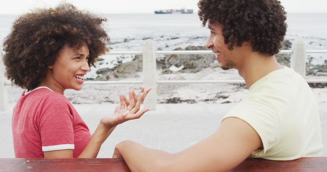 African american couple smiling while talking to each other sitting on a bench on the promenade - Download Free Stock Photos Pikwizard.com