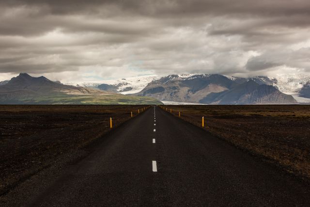 This image showcases a straight road leading toward majestic mountains under a cloudy sky. Ideal for use in travel and adventure-themed publications, nature blogs, and inspirational posts about journey and exploration.