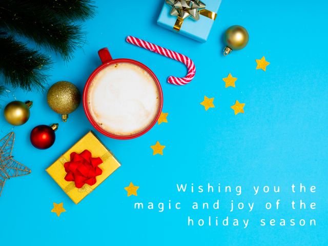 Image features a red mug with a warm drink, surrounded by Christmas ornaments, gifts, and a candy cane on a blue background. Ideal for holiday greeting cards, social media posts, festive season marketing materials.