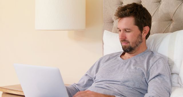 Man Relaxing in Bed While Using Laptop for Remote Work - Download Free Stock Images Pikwizard.com