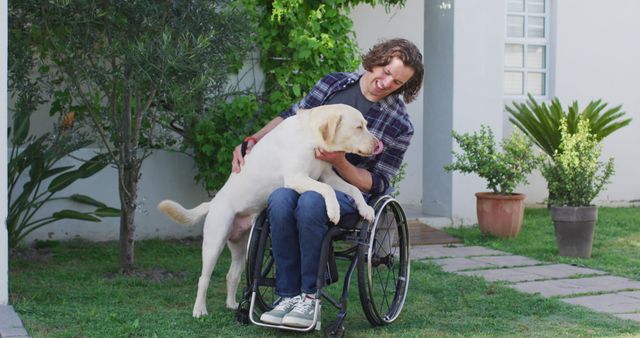 Young man sitting in wheelchair happily playing with his dog in a garden. The image portrays themes of friendship, joy, and companionship. Ideal for promoting inclusivity, disability awareness, and the bond between humans and animals.