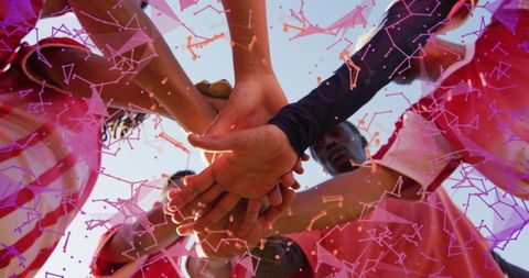 Male teammates joining hands in energetic red-jersey huddle with magenta network overlay