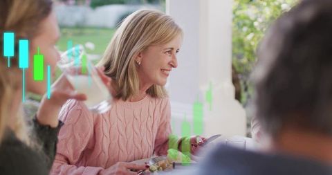Smiling mature woman at outdoor family dinner with candlestick stock chart overlay