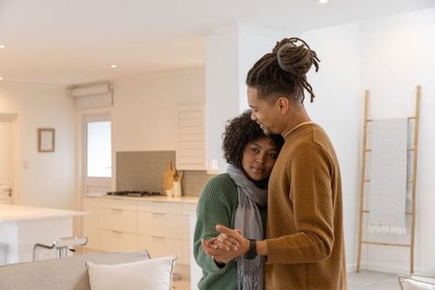 Diverse couple embracing and slow dancing in cozy modern minimalist kitchen interior