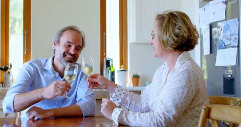 Couple Enjoying Wine and Laughter in Cozy Kitchen Setting
