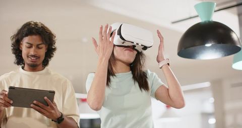 Asian coworkers testing vr headset in coworking space, woman experiencing immersive tech