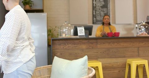 Barista serving coffee at cozy wooden cafe counter with red cups and pastries