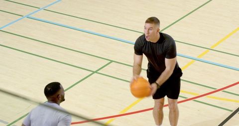 Athlete preparing jump shot on lined gym hardwood during pickup game with defender