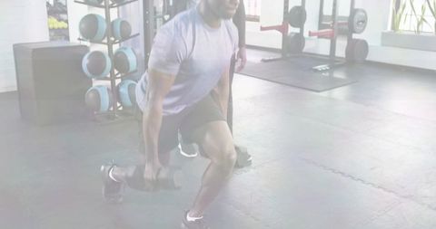 Man Performing Dumbbell Reverse Lunge in Functional Gym with Medicine Ball Rack