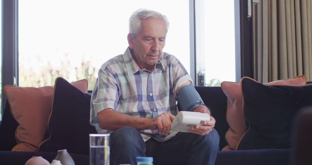 Image of focused caucasian senior man checking pressure. seniors health and nursing home lifestyle concept.