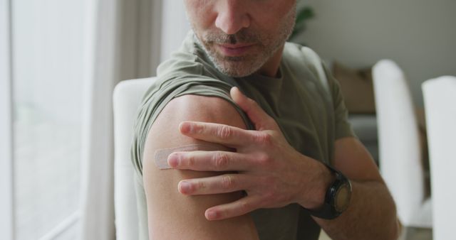 Portrait of caucasian man with vaccinated shoulder at home. vaccination for prevention of coronavirus outbreak concept