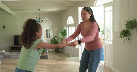 Mother spinning daughter in sunlit living room, joyful family bonding and playful care