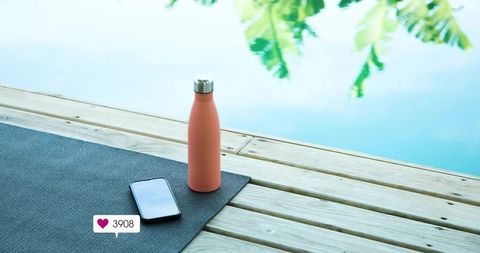 Coral Insulated Bottle and Smartphone Resting on Yoga Mat at Poolside Showing 3908 Likes
