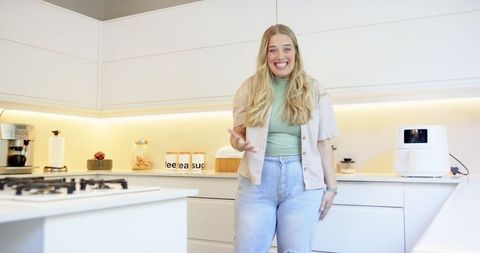 Woman cooking in modern minimalist kitchen with appliances