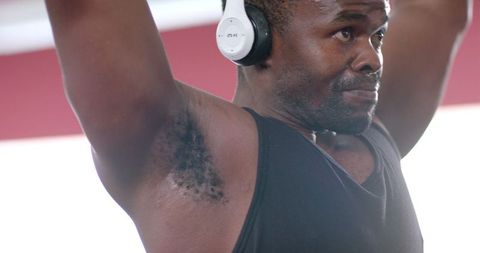 Focused Man with Headphones Lifting Weights in Gym