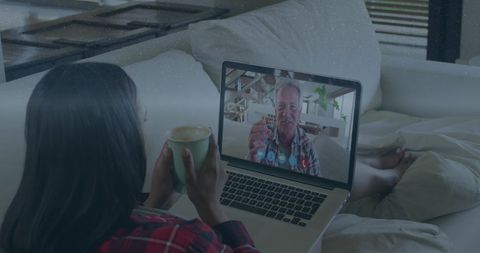 Woman video calling senior man on laptop with coffee