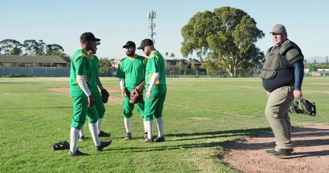 Diverse male baseball team gathering on mound preparing for game in sunny ballpark