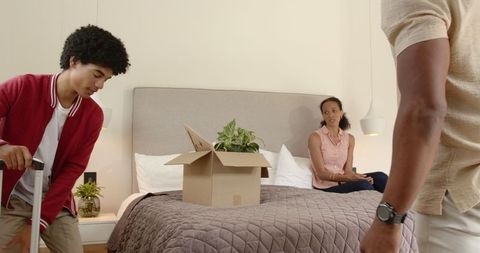 Diverse family unpacking box and plant in cozy bedroom