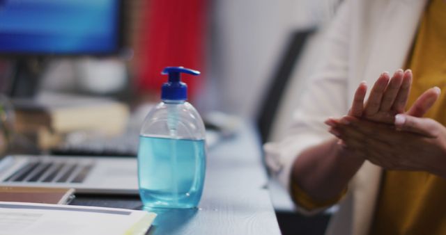 Hand Sanitizer on Desk with Person Cleaning Hands in Office - Download Free Stock Images Pikwizard.com