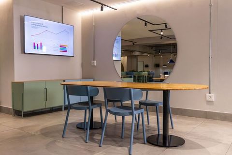 Contemporary coworking lounge featuring oval wooden table and blue molded chairs