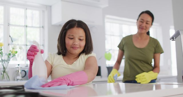 Mother and daughter cleaning kitchen together with rubber gloves - Download Free Stock Photos Pikwizard.com