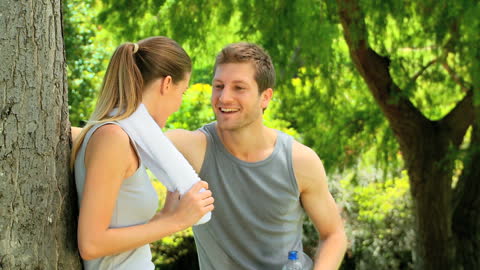 Couple Refreshing with Water After Workout in Scenic Park
