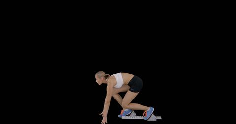 Athletic Woman Ready for Sprint in Start Position Against Black Background
