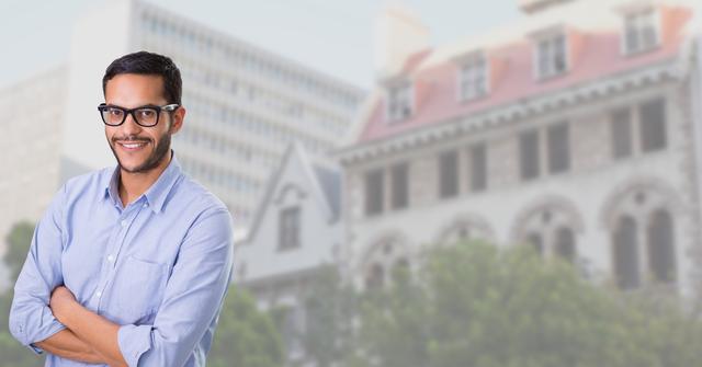 This image features a confident man standing with his arms crossed in front of an urban background with buildings. He is wearing glasses and a casual shirt, smiling at the camera. This photo can be used for business, professional, or lifestyle purposes, such as corporate websites, advertisements, or promotional materials.