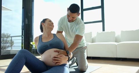 Pregnant Woman Doing Prenatal Yoga with Partner Support at Home