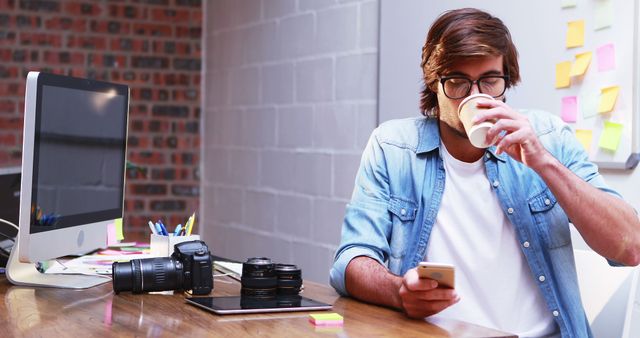 Casual photographer working from home, using phone and drinking coffee - Download Free Stock Images Pikwizard.com