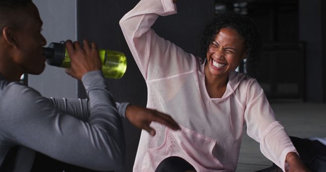 African american man and woman resting after game drinking water and laughing. urban fitness and healthy lifestyle.