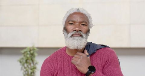 Dignified senior african american man standing with jacket over shoulder wearing maroon sweater