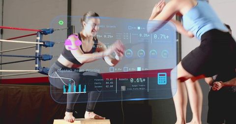 Female athlete doing box jumps with futuristic fitness hud overlay in boxing gym