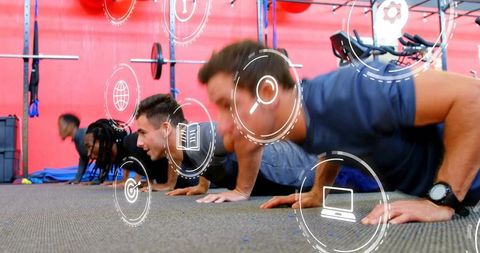 Men performing push-ups in gym during group strength training with digital icons