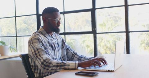Focused Professional Working on Laptop During Busy Office Day