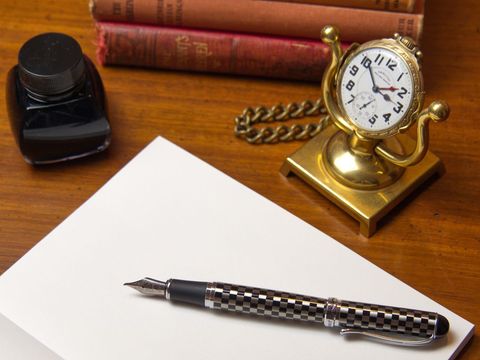 Vintage writing desk with pen, inkwell, books and clock