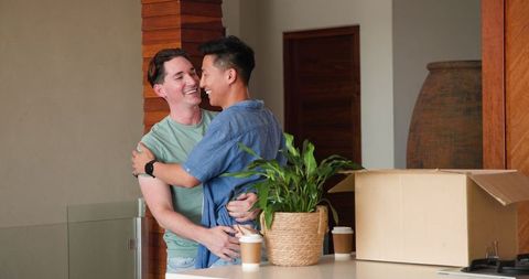 Joyful male couple celebrating first day in new home together