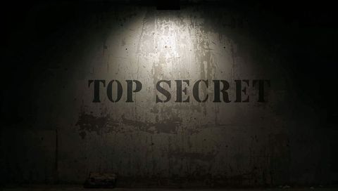 Top secret stencil on weathered concrete wall under overhead spotlight