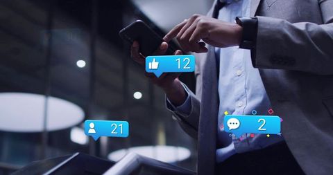 Businessman tapping smartphone while receiving social media notifications in modern lobby