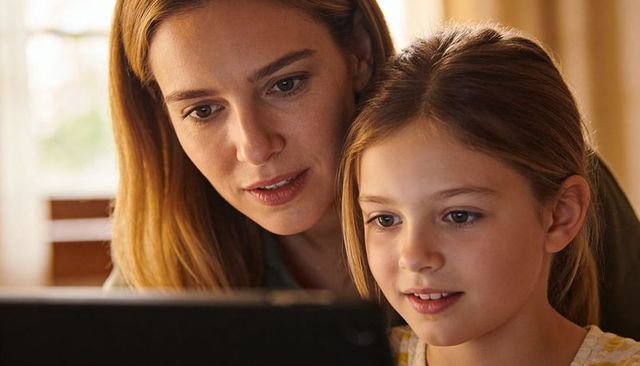 Mother and daughter reading tablet together at home sharing cozy learning and bonding moment