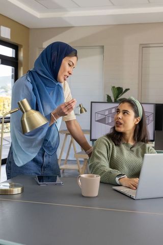 Muslim mentor guiding coworker while collaborating on 3d architectural design in office