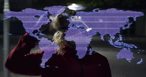 Silhouette Raising Hand Activating Purple Hologram World Map at Night Plaza